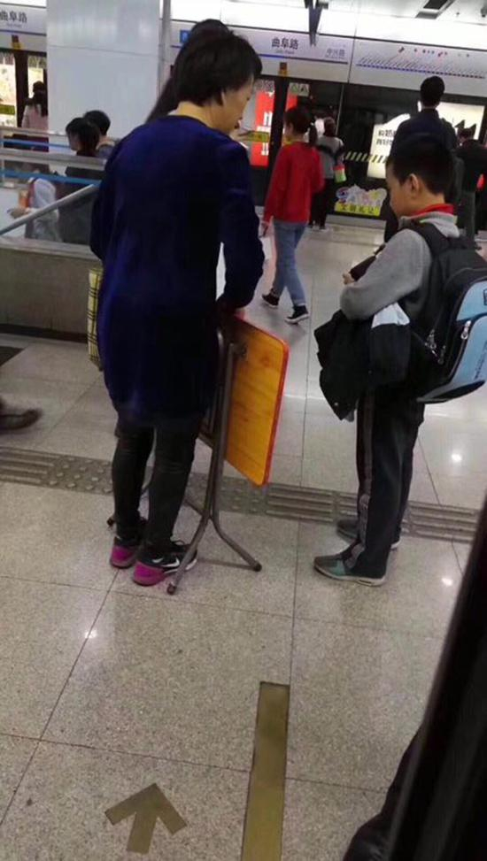 11月6日，上海地铁8号线曲阜路站，家长带孩子乘地铁，手提一张折叠桌。 网友供图