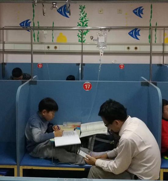 11月6日傍晚，普陀区人民医院内，一名学生边输液边写作业。&nbsp;新民晚报记者 孙中钦 图