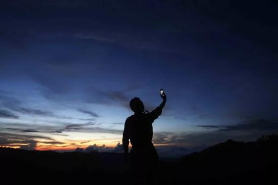 ▲阿超在山顶费力寻找信号。