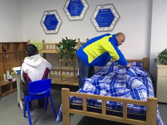 救助站内，李福强正在为小樑整理床铺。 黄尖尖 摄