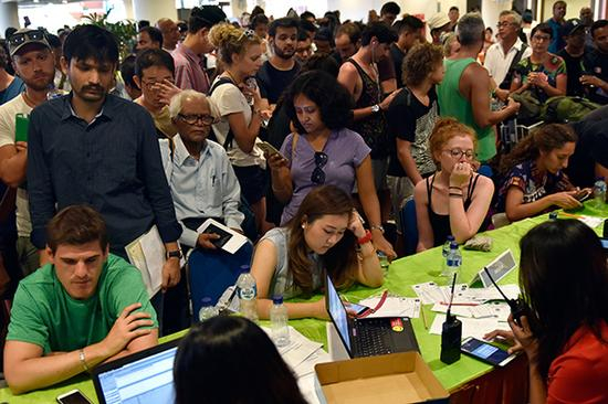 2017年11月27日，在印度尼西亚巴厘岛伍拉莱国际机场，乘客与机场工作人员沟通。 &nbsp;新华社 图