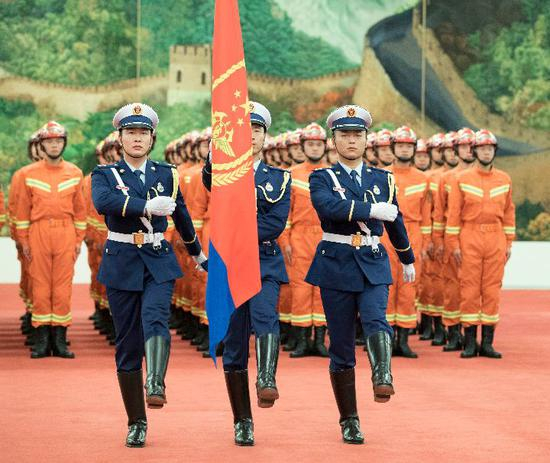 这是仪仗队员护卫着中国消防救援队队旗正步行进。新华社记者 李涛 摄