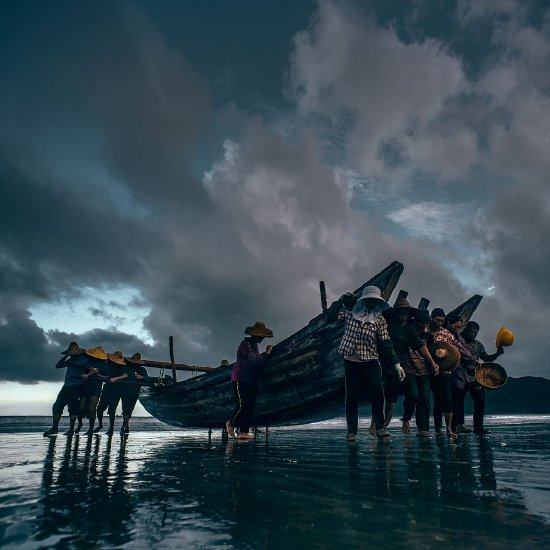 　　2023年7月15日，广东汕尾，台风“泰利”即将来临，海丰县天空乌云密布，渔民们在海滩上紧密协作，合力将渔船及捕捞工具抬向岸边。