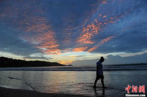 资料图：游客从海滩上走过。洪坚鹏 摄