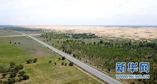 　　▲汽车行驶在榆（林）靖（边）高速公路上（8月1日无人机拍摄）。穿越毛乌素沙漠的榆靖高速，是中国建成的第一条沙漠高速公路。
