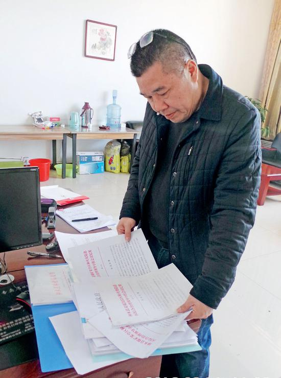 神木考考赖沟综治项目负责人喻建林翻阅政府各种批文，思考被清场的原因。摄影/本刊记者 周群峰