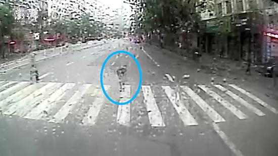 一名女性行人在斑马线上，给雨中让行的公交司机鞠躬道谢。 十堰公交车监控视频截图
