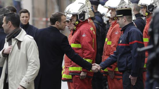 2018年12月2日，马克龙在巴黎街头与一名消防员握手。