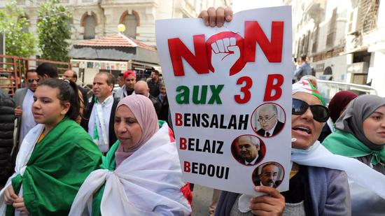 阿尔及利亚示威者身披国旗，高举标语