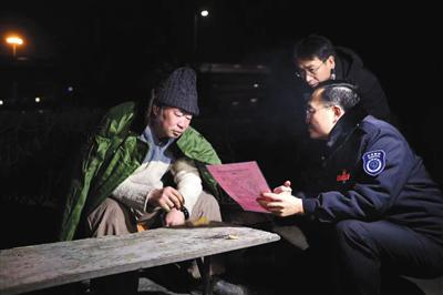 　　2018年12月31日，四惠桥附近的绿化带中，朝阳区民政局的工作人员给流浪乞讨人员送棉衣，并讲解救助政策。 新京报记者 彭子洋 摄