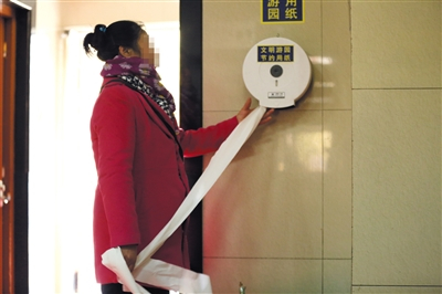 2017年3月4日，天坛公园公共厕所内，一名游客撕取免费厕纸。资料图片/视觉中国