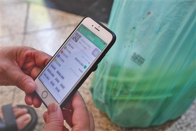 8月2日，杭州，一位志愿者通过扫描二维码对垃圾投放者进行评分。