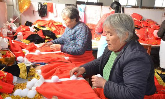 正在对演出服做预加工的老人。在大集，老人们个个都是宝，没一个闲着的