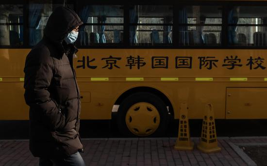 △&nbsp;3月4日，北京望京，戴口罩的行人经过北京韩国国际学校外的校车。