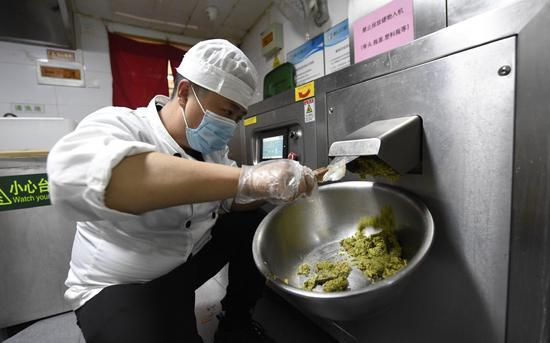 新川面馆月坛店工作人员将厨余垃圾倒进自动处理设备，经过处理，10余公斤的厨余垃圾仅剩1公斤左右。摄影/新京报记者 吴宁