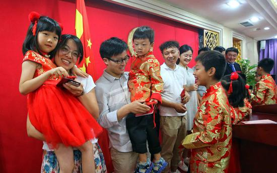 ▲七夕节，某婚姻登记处，身着传统唐装的“小花童”为新人送上祝福许愿牌。&nbsp; 图/新京报网