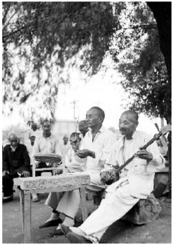 　　1953年7月21日，辽宁抚顺市工人养老院。70岁的张静明在院内树荫下弹三弦，60岁的李秀峰打鼓说书。赵眏摄 （本报资料照片）