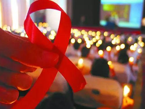 海南一所大学里的500多名青年志愿者在红丝带前点燃蜡烛来纪念“世界艾滋病日”。