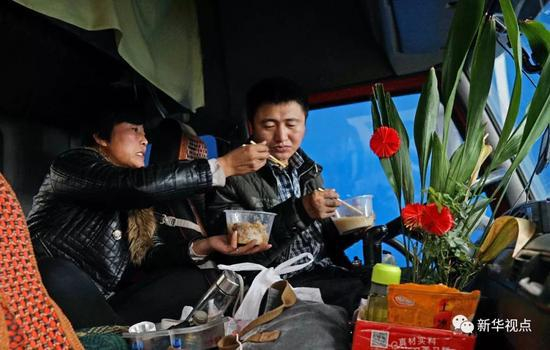↑1月17日，在浙江省杭州市的一家工厂，孔令建（右）和王艳青在驾驶室里吃饭。 新华社记者才扬摄