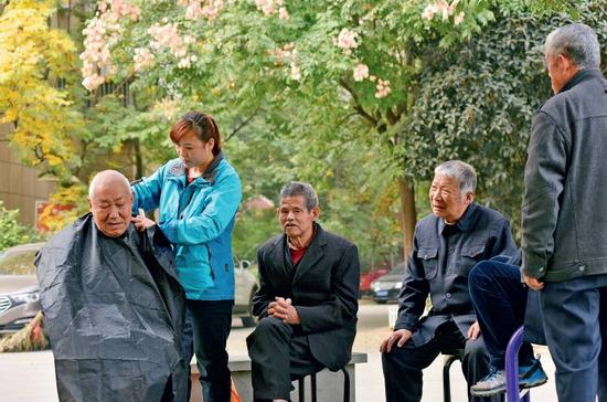 　　11月9日，在安徽省合肥市蜀山区井岗镇欣塘家园小区广场，47岁的李泽翠在为小区里的老年人免费理发。随着中国人口老龄化的加剧，养老金方面的需求日渐增长。图/视觉中国