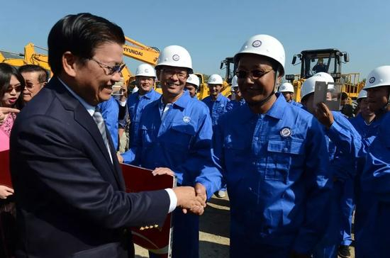 　　▲资料图片：在老挝琅勃拉邦，老挝总理通伦（左）在中老铁路开工仪式上与中方员工握手。（新华社）