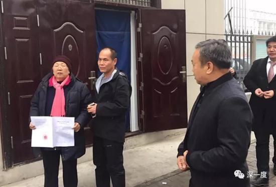 周远母子在法庭外展示判决书。
