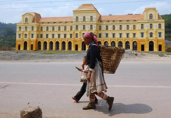 　　▲资料图片：老挝民众走在该国北部的磨丁经济特区。2016年11月28日，中老两国共同签署了《中国老挝磨憨-磨丁经济合作区共同发展总体规划》，磨丁特区将成为东盟-中国自由贸易区合作的国家门户和前沿口岸。（法新社）