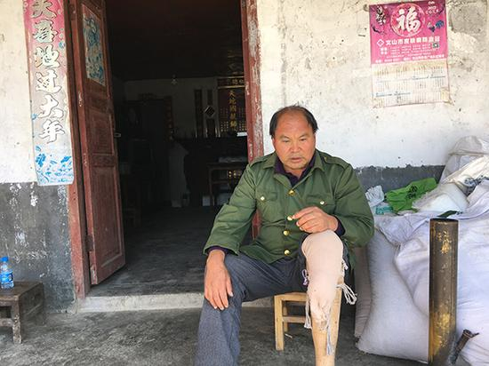 左腿截肢的陈正方坐在自家门口，安装了假肢还能走路，但走的时间太长，接触部位会磨破皮。
