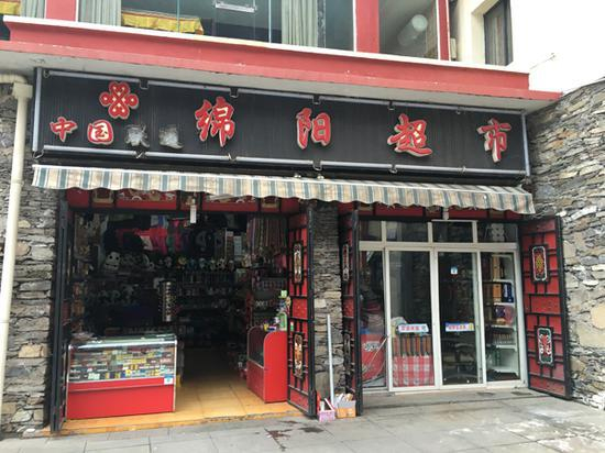 周琴家开的”绵阳超市”距离九寨沟景区入口约800米，因游客还不多，她一个人就可照看这家超市。