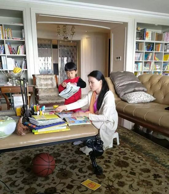 ▲朱小贞和小儿子在客厅里，背后书架为起火点。受访者供图