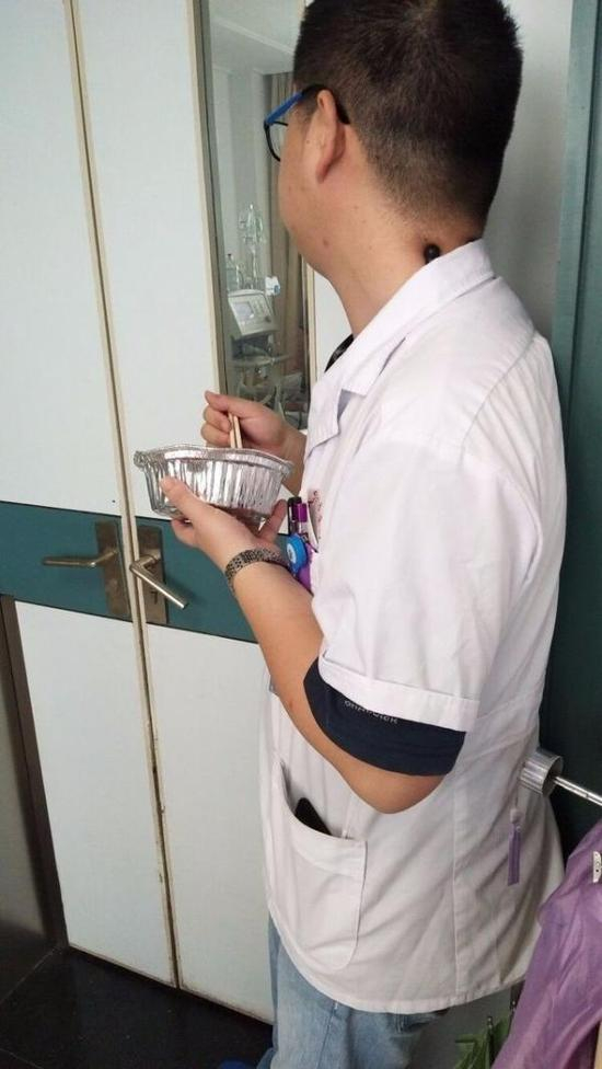 宋医生一边吃盒饭，一边盯着病房里的患者。 都市快报 图