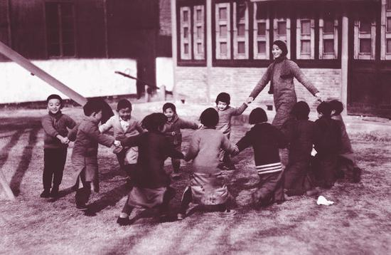 　　金陵女子文理学院校园即景 1935年12月30日 1935年12月30日，南京金陵女子文理学院的一位年轻的幼教老师带着孩子们在草坪上做游戏。 原载《老照片》第6辑
