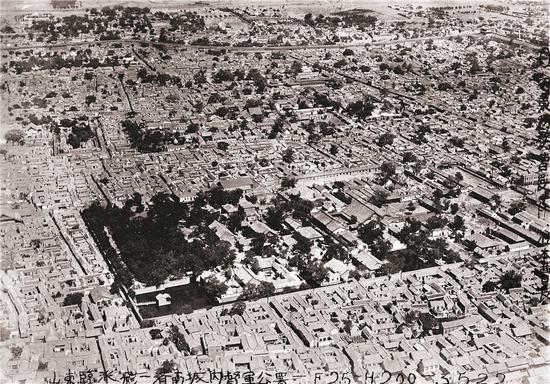 　　珍珠泉大院 1928年5月22日 这张航拍照核心景象是珍珠泉大院。公署内建筑自南向北按中轴线分布，从大门算起有七进院落，各院错落有致，清巡抚大堂是中轴线上最宏伟的建筑。后院之后是一个遍植树木的花园，西与濯缨池相通，池中可见古戏台（今仍尚存）。由濯缨池沿玉带河上溯，可见一个方形泉池，这就是昔日的珍珠泉，泉池比今天略小。这张照片的涵盖面积超过了济南老城的四分之一，包括珍珠泉大院东面、东南面的城内建筑、新东门和东南角楼——九女楼。从照片中还能看到东圩子墙，两墙之间有种着树的小山坡。此外，在珍珠泉大院西面，还能看到王府池子，今天它大致是方形，当年却是明显的“L形”。 原载《老照片》第75辑 p126-127