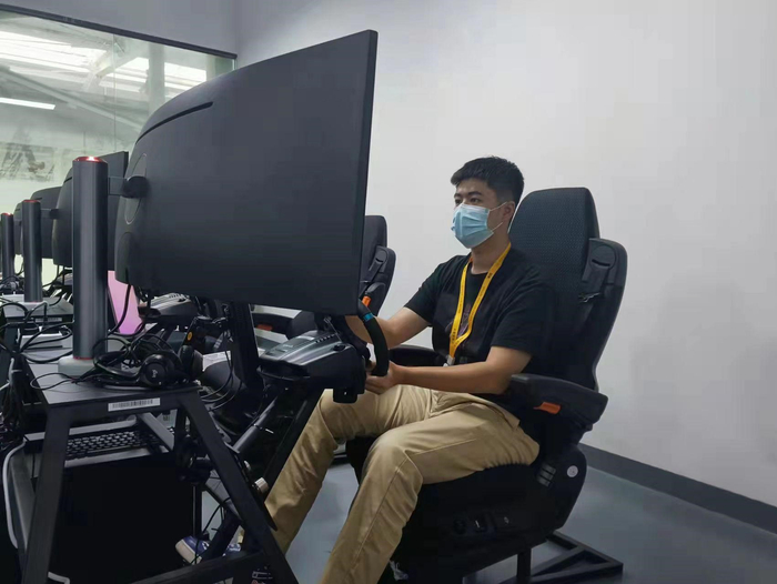 ▲人机协同能够有效提高自动配送车的效率和安全性。图为陈泽深正在驾驶模拟器前监测自动配送车的行进路线。（吴用 摄）