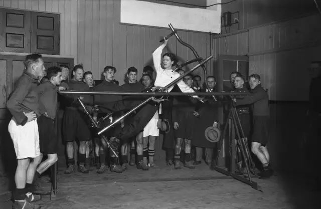 一群男人在欣赏一位女性健身，足以看出女性健身在当时的风靡程度和接受度