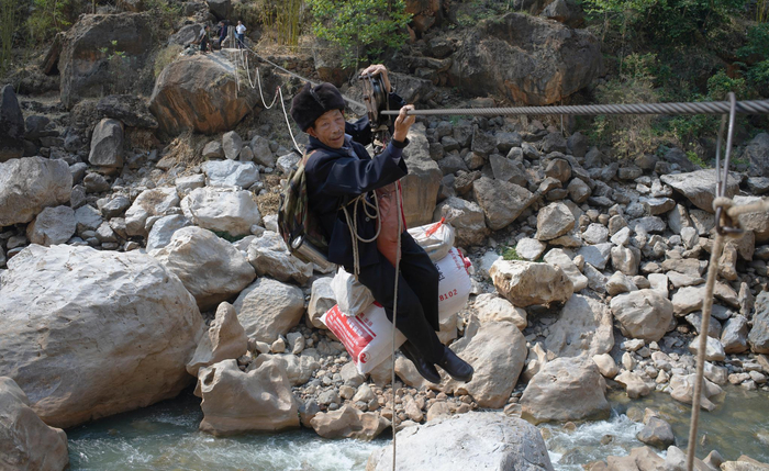　　71 岁的卯稳树溜索过江时，还带着两编织袋包裹，这已是他几十年的反复动作。大约40 分钟，人和行李全部溜索过江到对岸。
