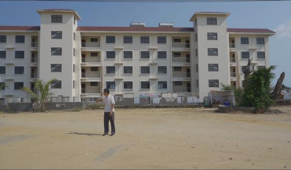 　　李景奎介绍金阳光小区曾经的楼宇布局，他身后是没被拆除的3栋职工宿舍，照片右边是曾经充满欢声笑语的古树。 &nbsp;澎湃新闻 图