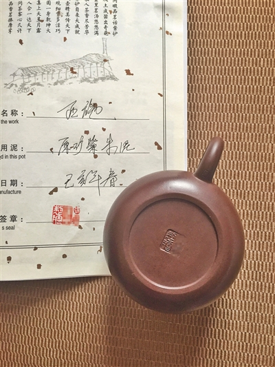 　6月22日，在宜兴中国陶都陶瓷城买到的刻有国家工艺美术师徐某名字的紫砂壶，商家现场模仿签名售卖。