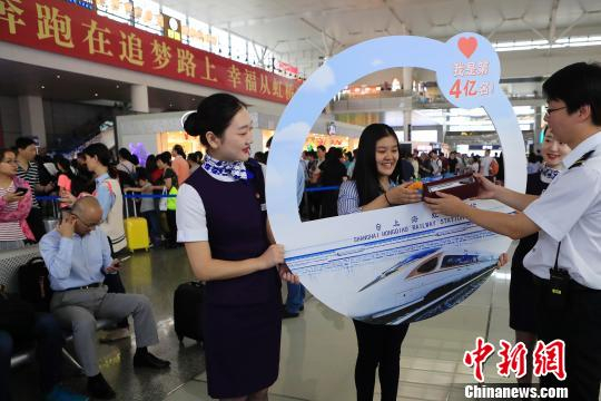  上海虹桥站开站以来的第4亿名旅客沈子怡接过工作人员送上的礼物。　殷立勤 摄