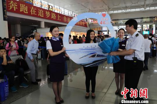  上海虹桥站开站以来的第4亿名旅客沈子怡接过工作人员送上的礼物。　殷立勤 摄