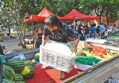 6月23日，海淀区某小区内，一名女子正在车上搬运蔬菜水果。