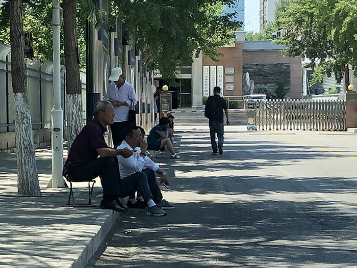  2019年7月3日上午，北京市丰台区市场监管局门前的路边，几名代办中介盘踞在这里等待客户。新京报记者 吴江 摄