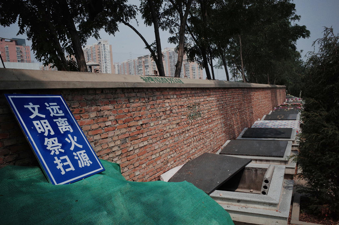 墓地焚烧炉被绿网遮盖，围墙边有文明祭扫指示牌。实习生 陈婉婷 摄