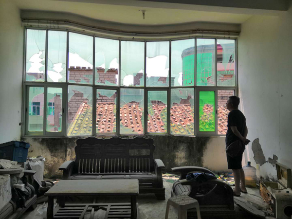 　念斌站在被打砸一空的老屋玻璃窗前。