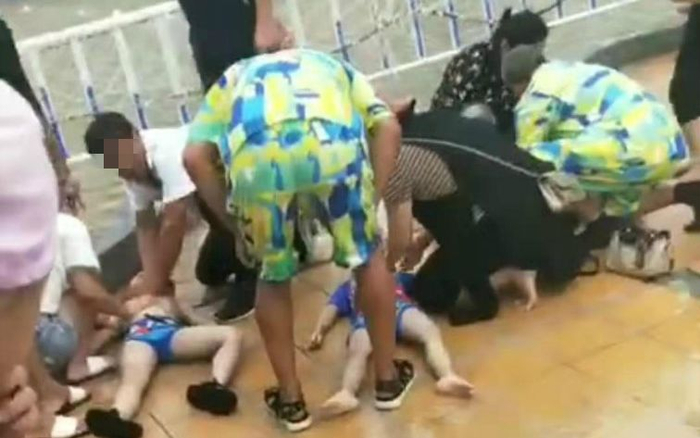 多名儿童躺在地上，有人正在按压儿童胸口。视频截图