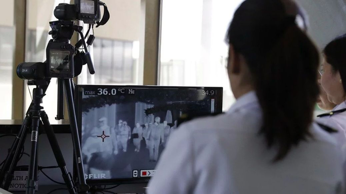 机场工作人员使用热扫描仪检视抵达的乘客