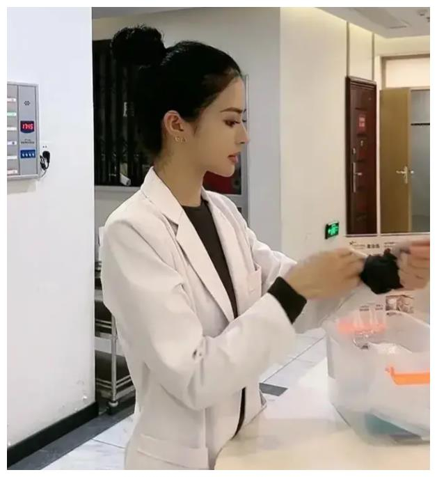 从画面看,这名女医生正在整理自己的袖子,像是刚穿上工作服准备上班的
