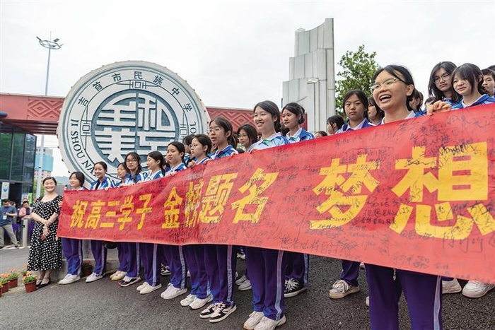 6月7日,吉首市民族中学校门外,在校学生为奔赴高考考场的考生加油