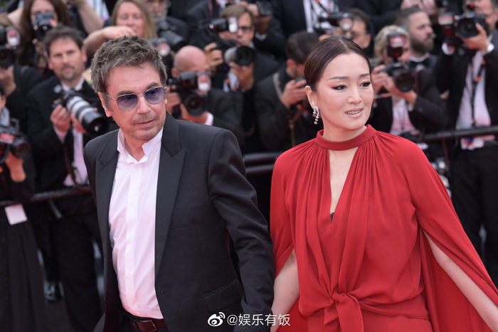 巩俐身穿红色裤装,牵手丈夫让-米歇尔·雅尔出席戛纳首映红毯