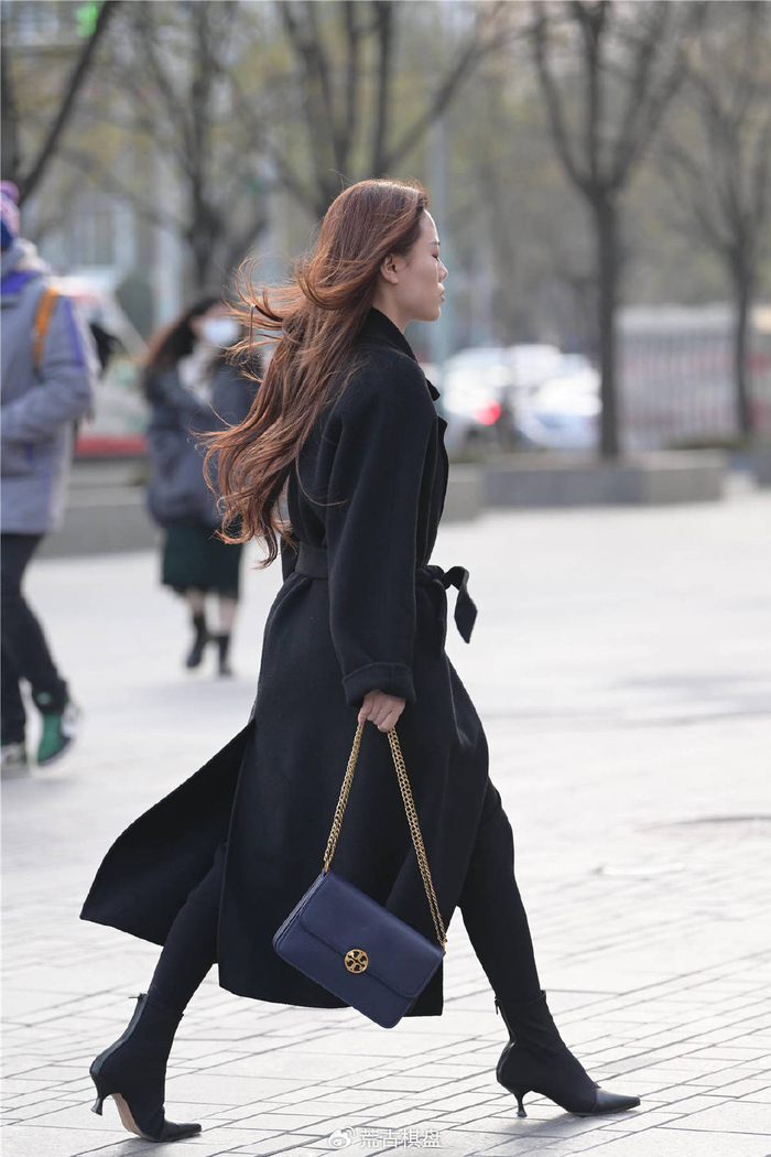 美女选择一款黑色的呢子大衣,衣摆很长,遮住短裤,所以更有保